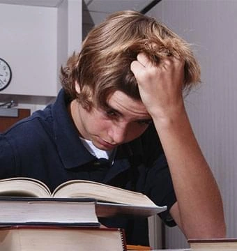 A man with his head in his hand over a book