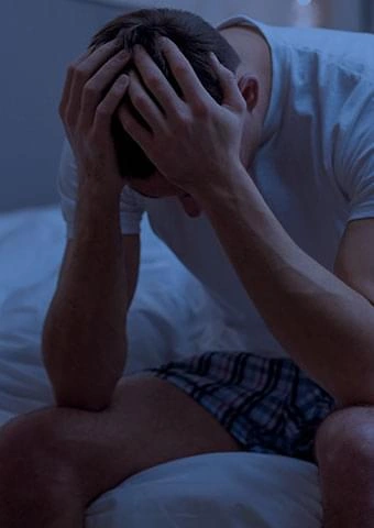 A man sitting on the edge of a bed, stock photography from a vendor image pack