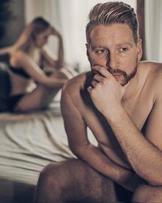 A man sitting on the edge of a bed, stock photography